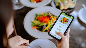 Technology makes life so much easier for young Asian woman using mobile app device on smartphone to place a food order in a restaurant.