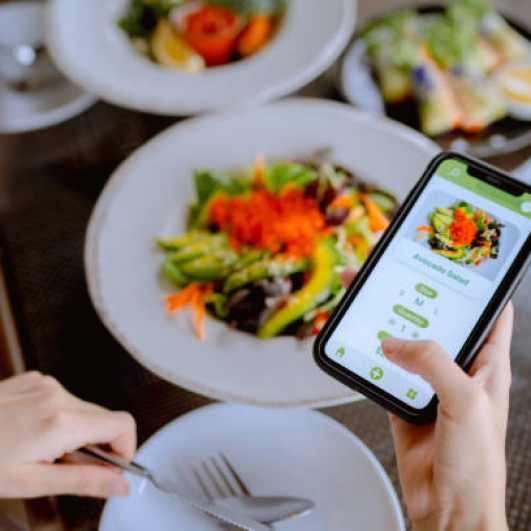 Technology makes life so much easier for young Asian woman using mobile app device on smartphone to place a food order in a restaurant.
